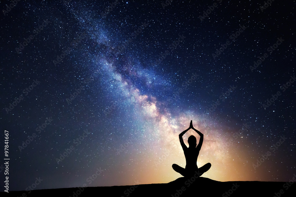 Milky Way and silhouette of a woman practicing yoga.
