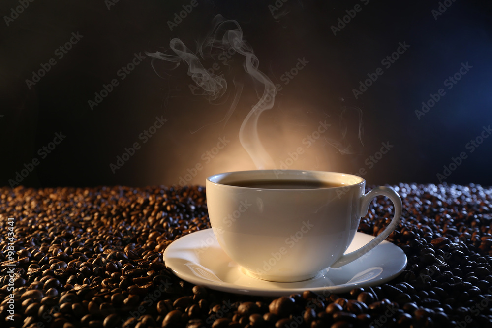 黑暗背景下咖啡豆中的一杯热咖啡