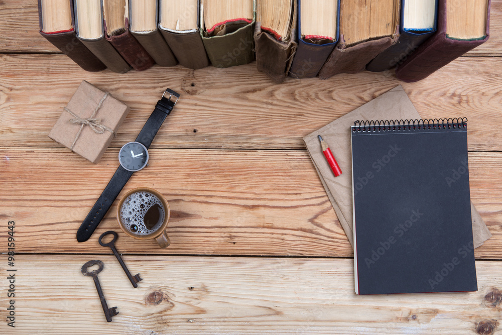 木制桌面俯视图，包括书籍、钥匙、手表、记事本和