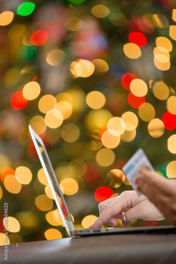 使用笔记本电脑进行假日购物，在圣诞树的灯光下拍摄