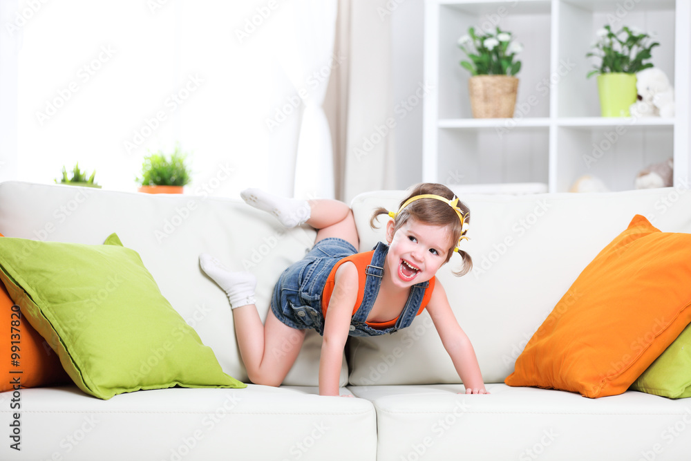 快乐的小女孩在家的沙发上玩耍