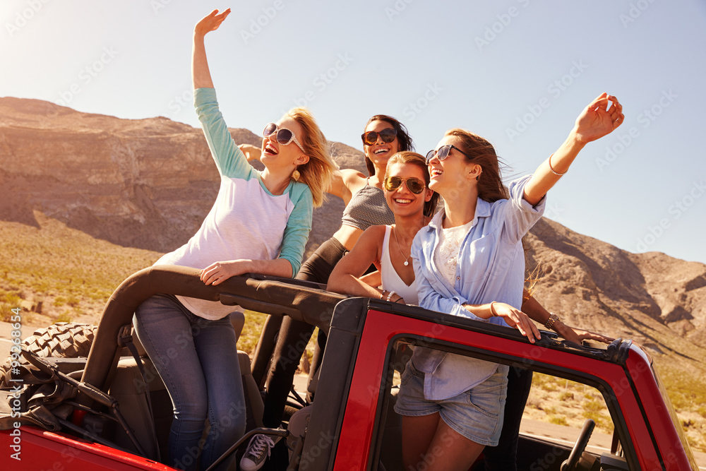 四位女性朋友站在敞篷车上旅行