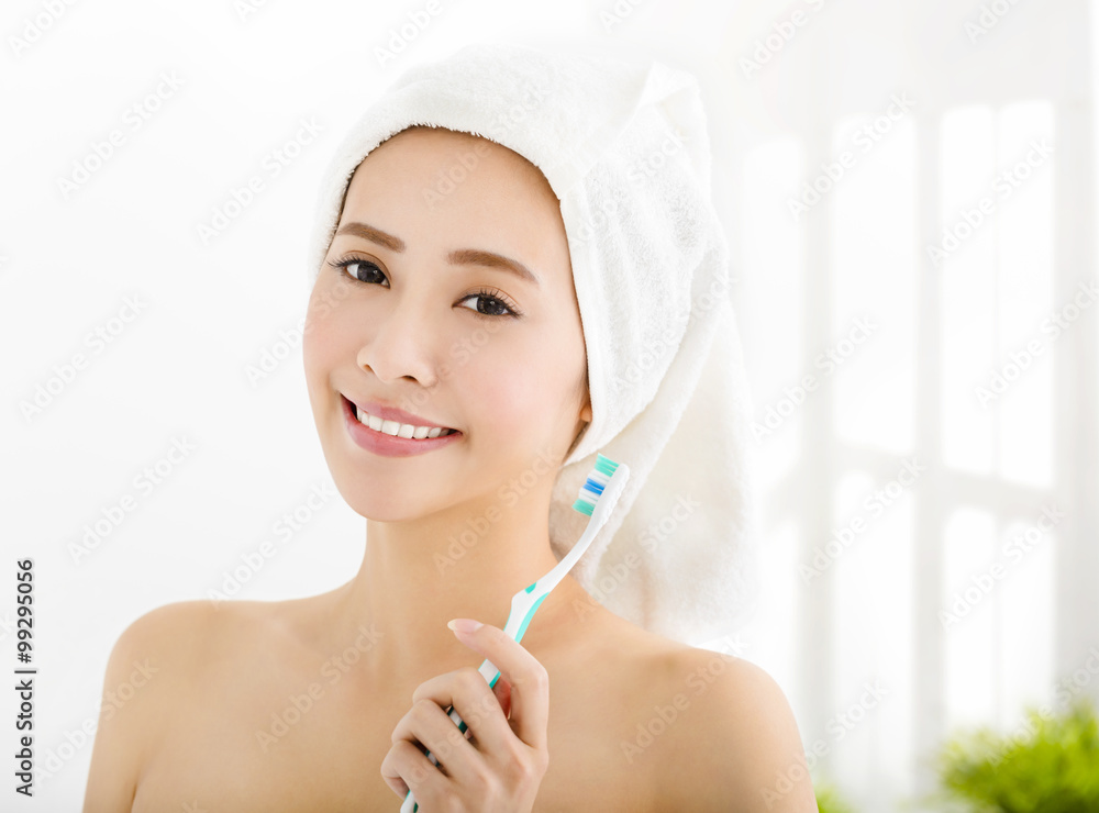 smiling young woman with  towel on  head and holding toothbrush