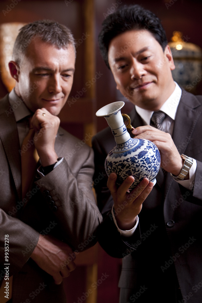 Mature businessmen admiring an antique Chinese vase