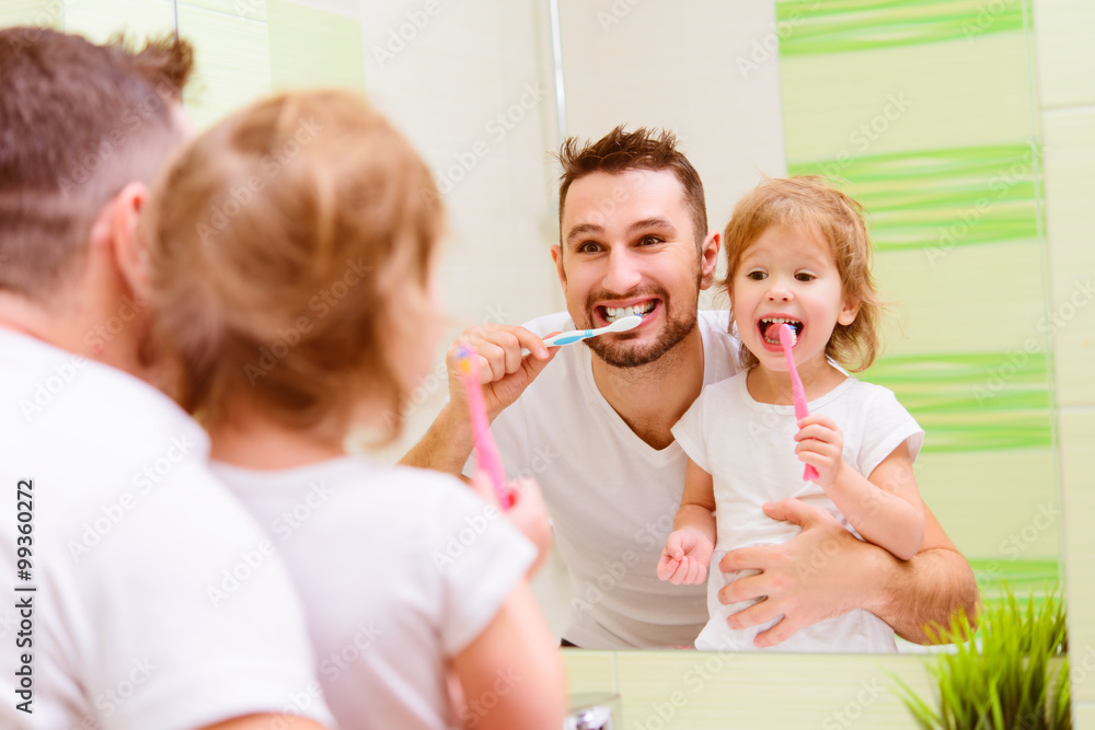 快乐的家庭父亲和小女孩在浴室刷牙