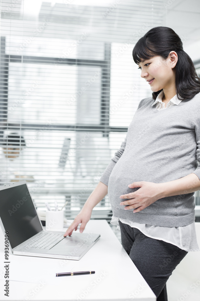 怀孕的女商人使用笔记本电脑