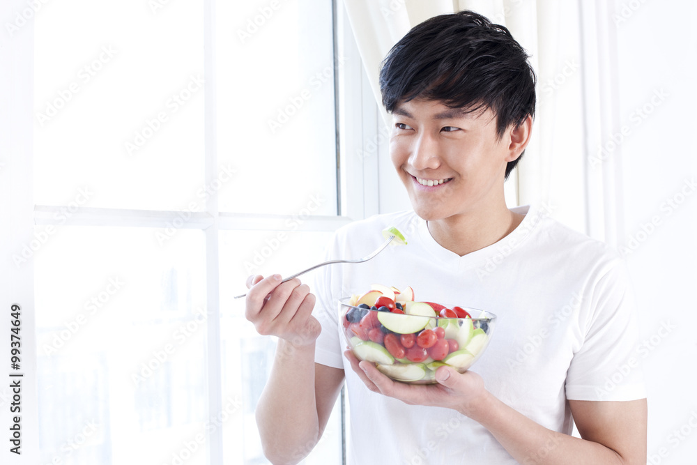 Young man eating fruit salad