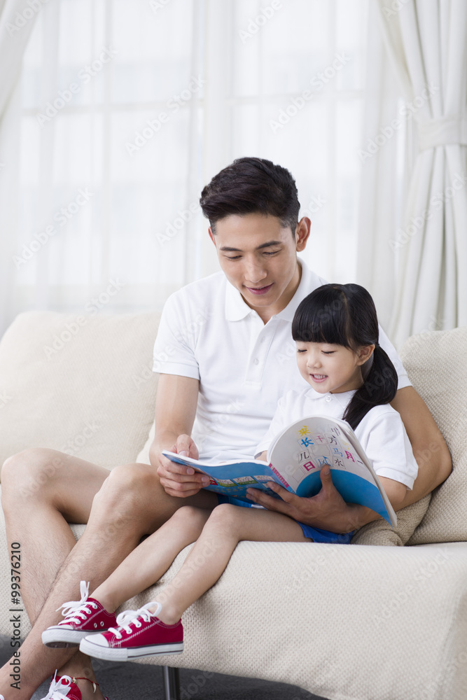 父亲和女儿在沙发上看书