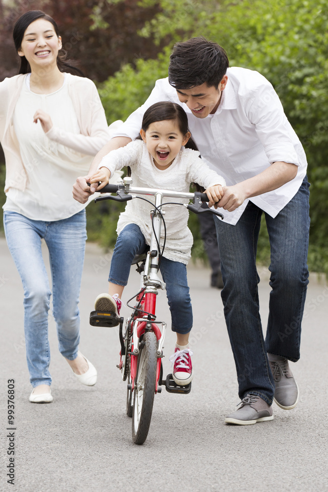 年轻父母教女儿骑自行车