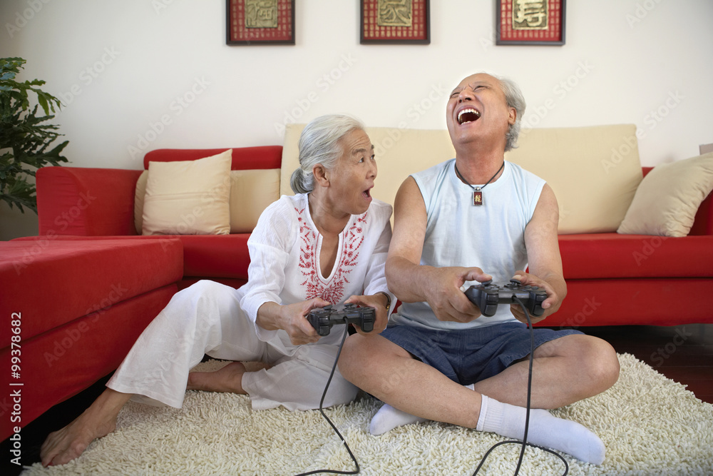 老年夫妇玩电子游戏，开怀大笑