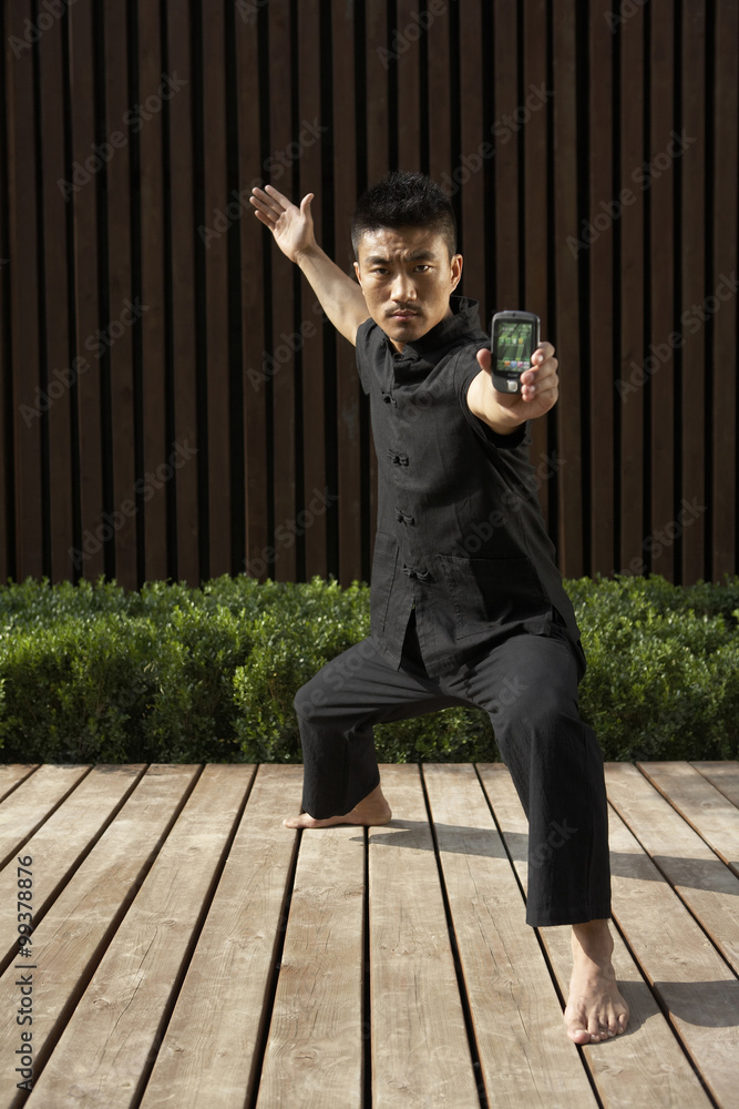 Man Practicing Martial Arts While Holding Cell phone