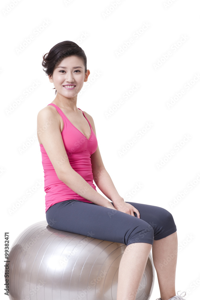 快乐的年轻女人坐在健身球上
