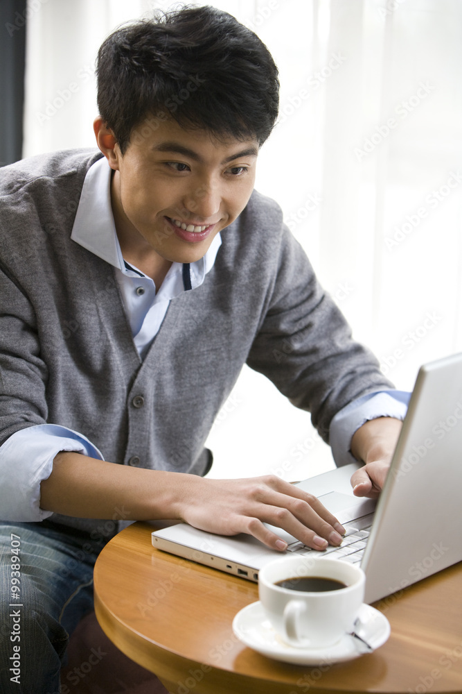 微笑的男人在咖啡店用笔记本电脑