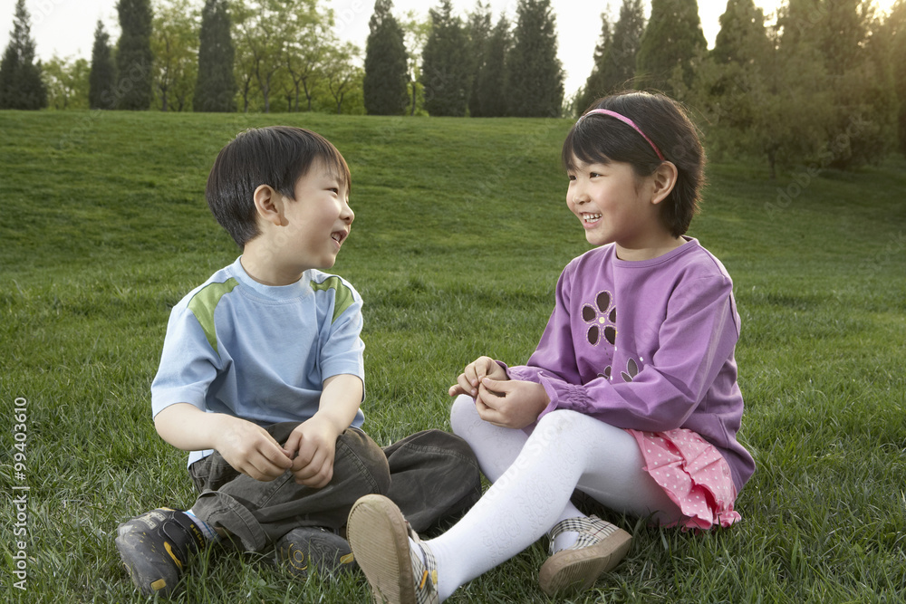 年轻男孩和年轻女孩坐在公园里聊天