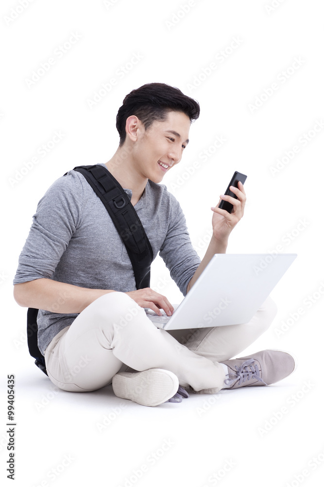 Happy male college student with laptop and smart phone