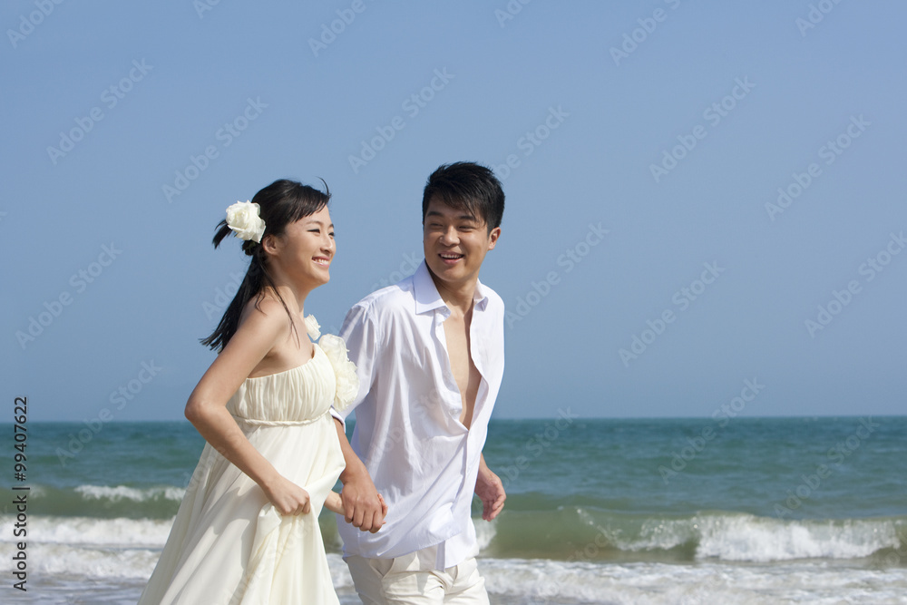 快乐的新婚夫妇在海滩上奔跑