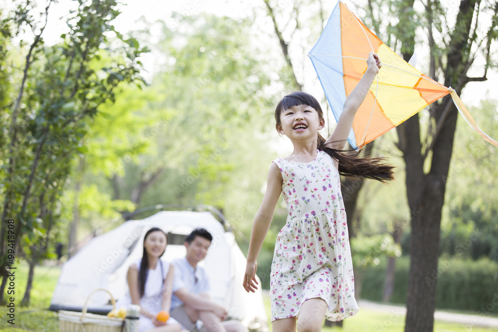 快乐的女孩带着风筝在草地上奔跑