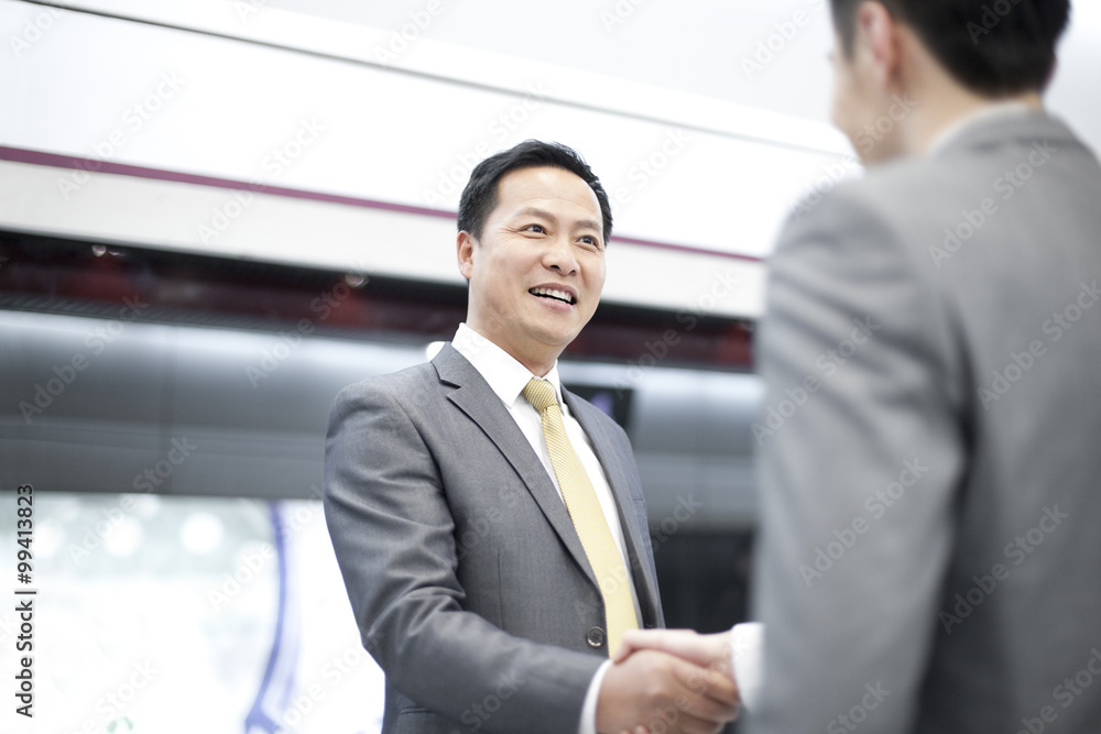 Business partners shaking hands on subway platform