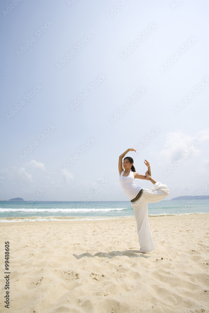 年轻女子在海滩上做瑜伽