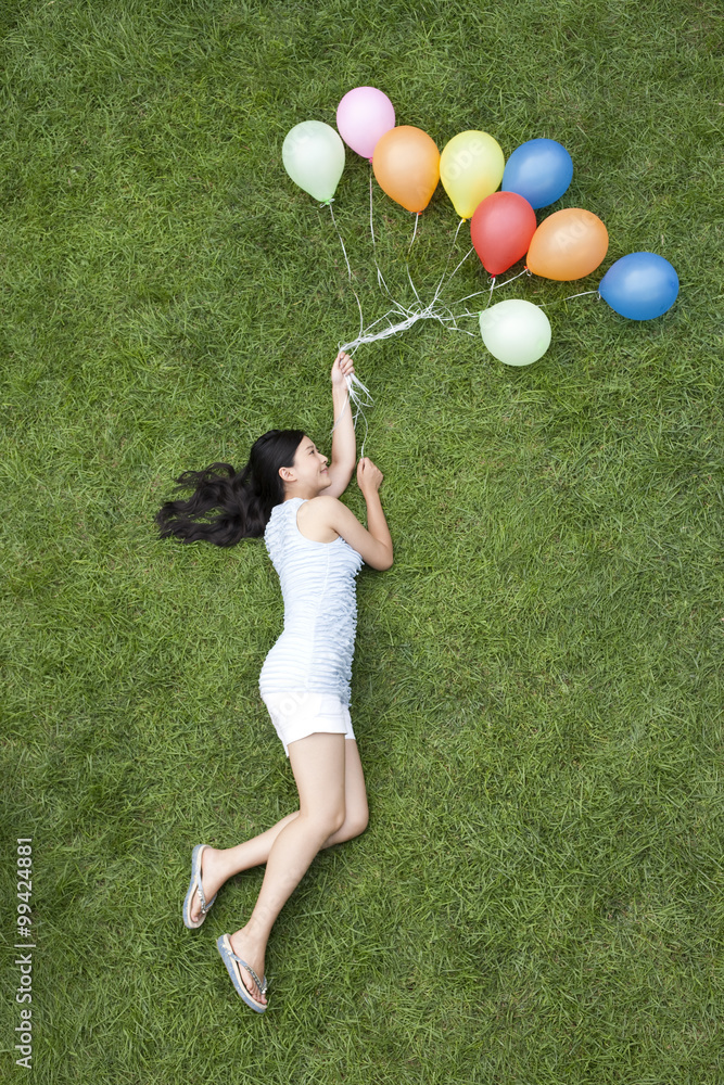 草地上拿着气球的年轻女子