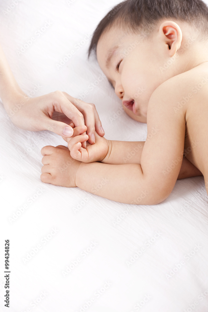 Mother holding sleeping babys hand