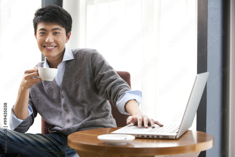 一个年轻人微笑着拿着一杯咖啡