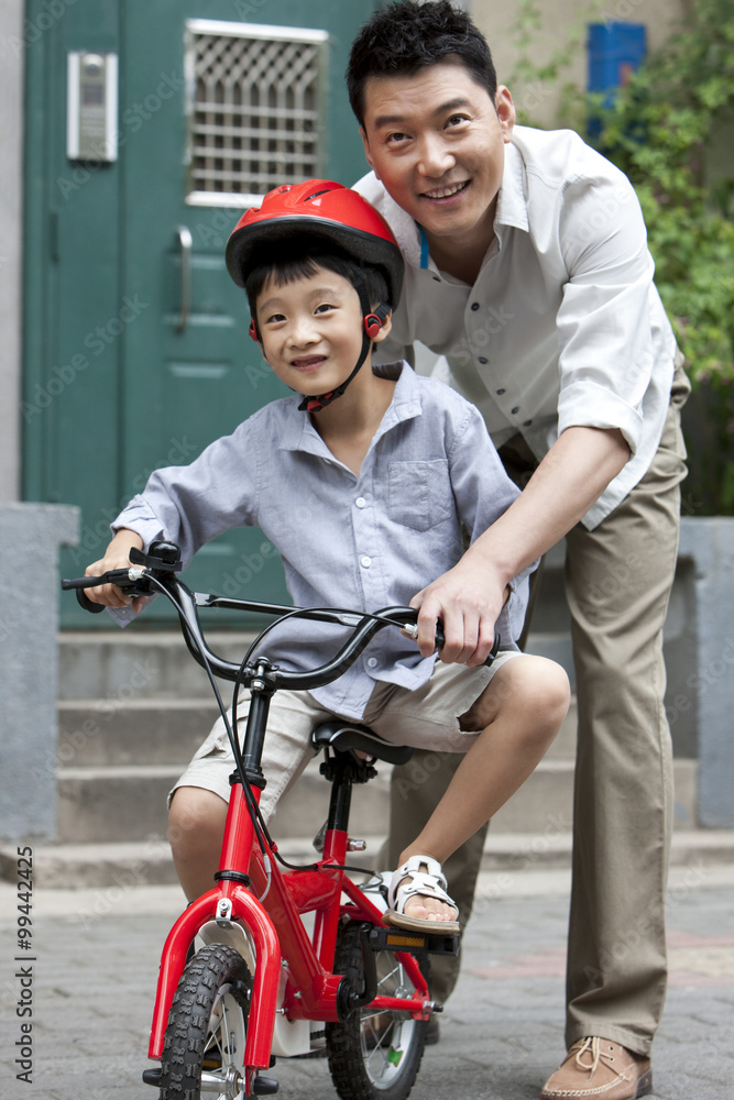 年轻的中国父亲训练儿子骑自行车