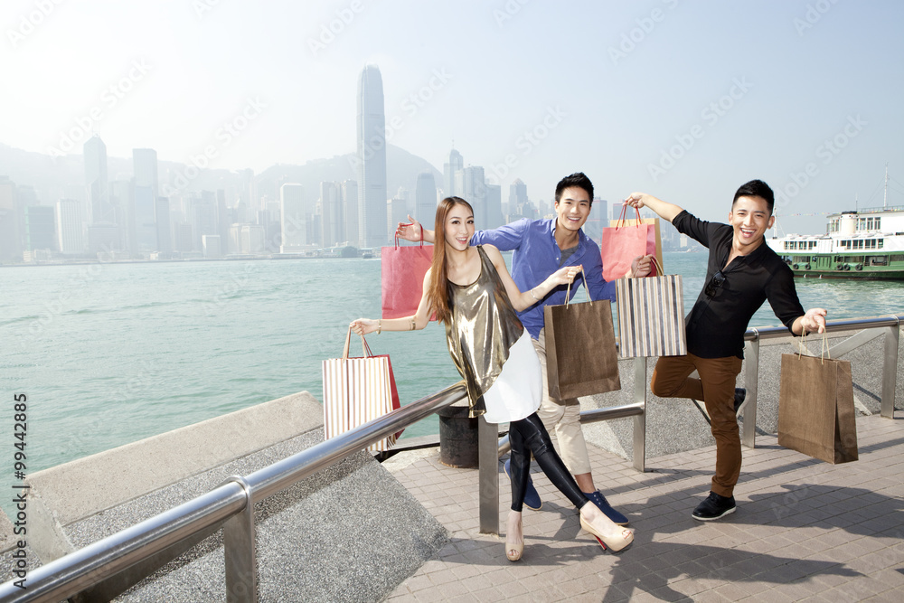 香港维多利亚港带着购物袋的兴奋年轻人