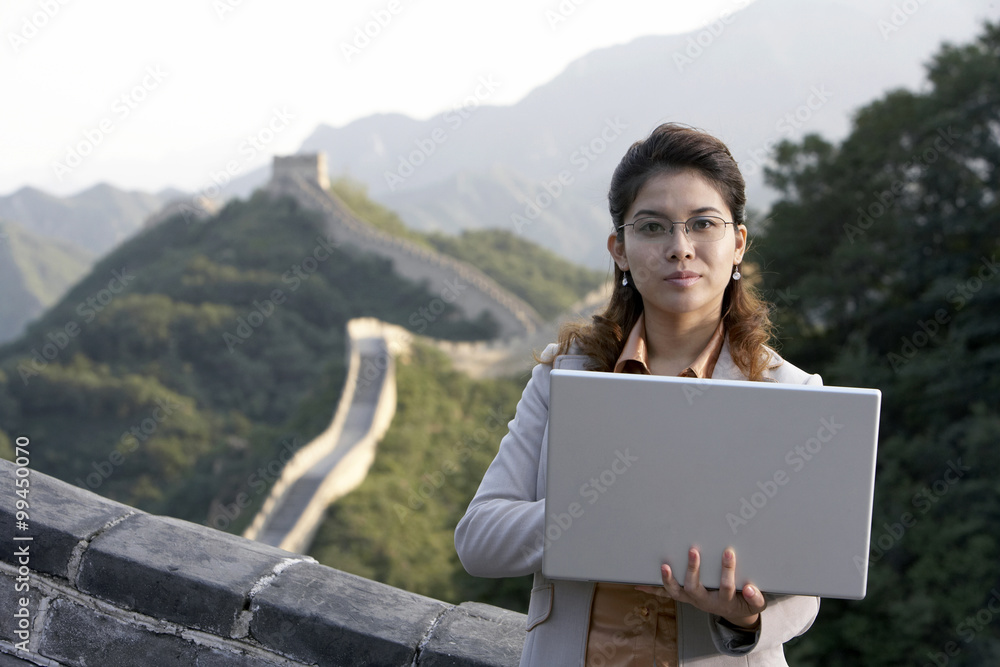 女商人在笔记本电脑上打字，在中国的长城上
