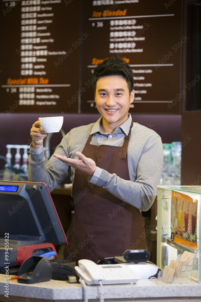 Male coffee store clerk with cup of coffee in hand