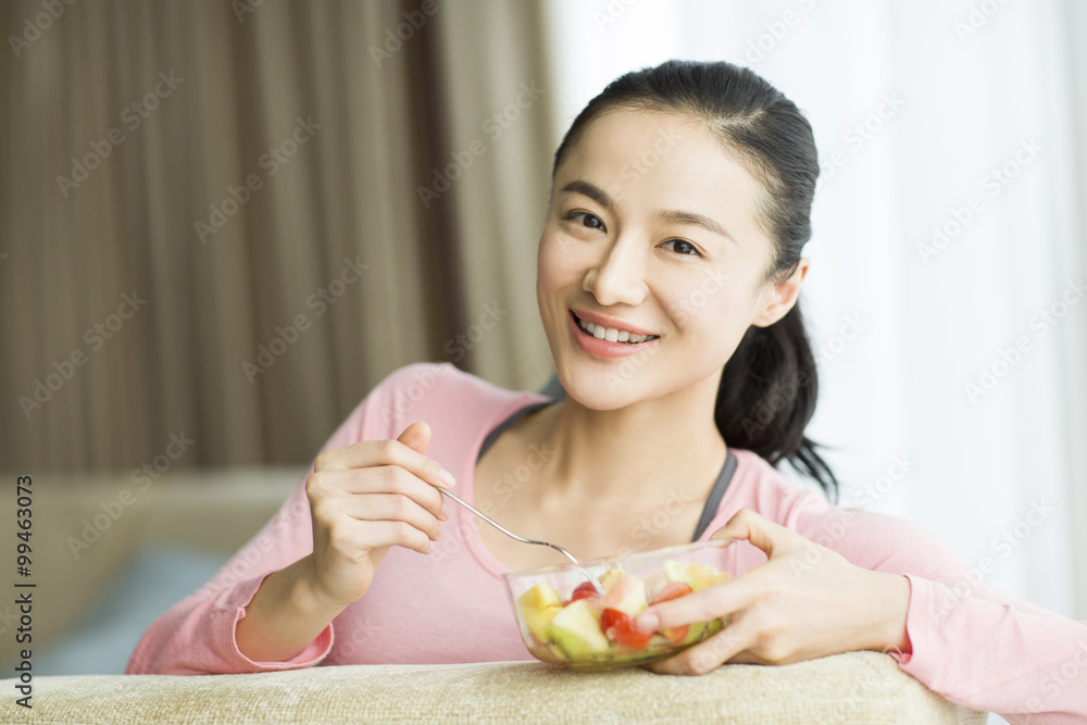 快乐的年轻女人吃水果沙拉