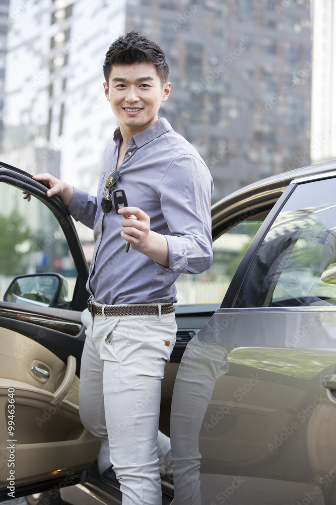 Young man posing with keys to his new car
