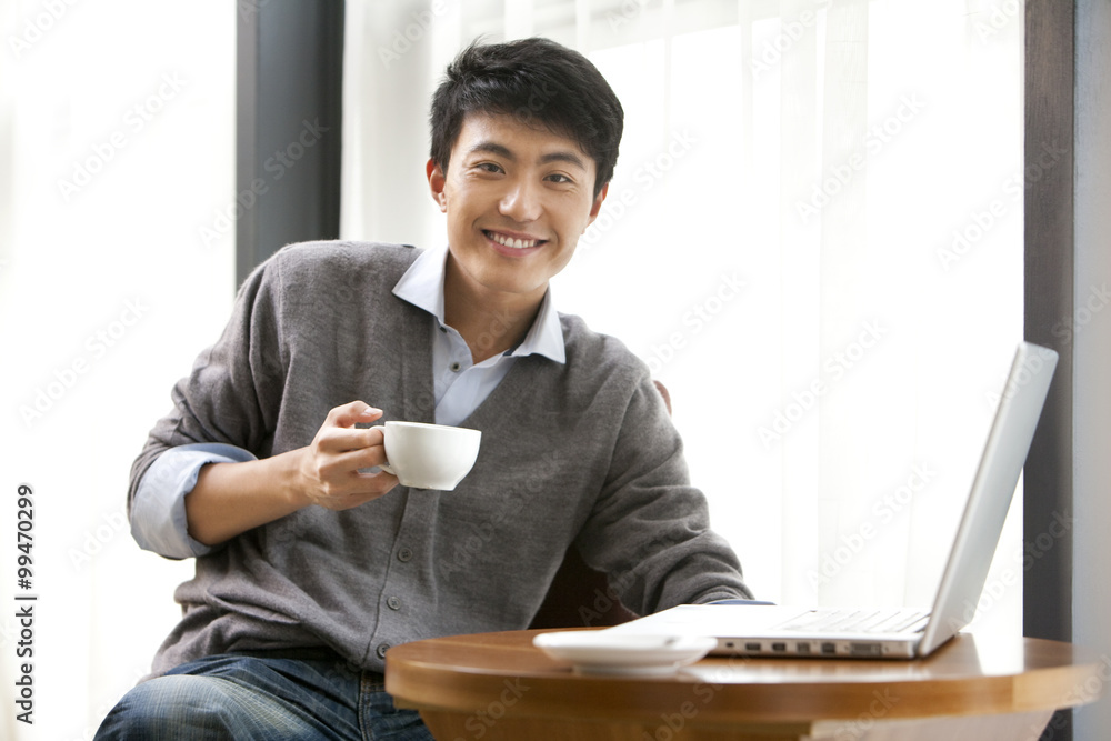 一个年轻人微笑着拿着一杯咖啡