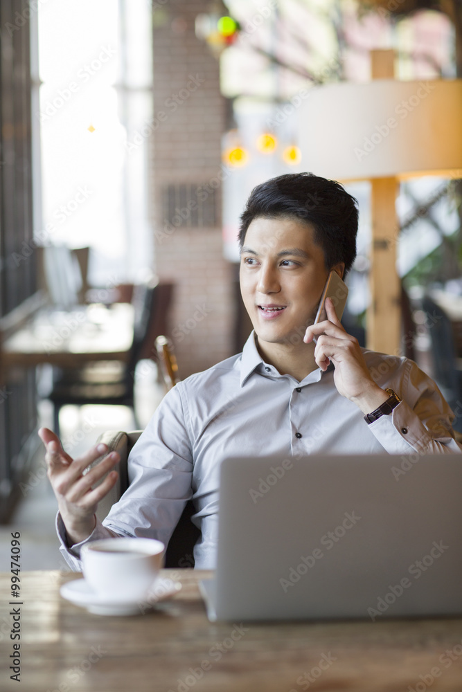Young man talking on phone in cafe