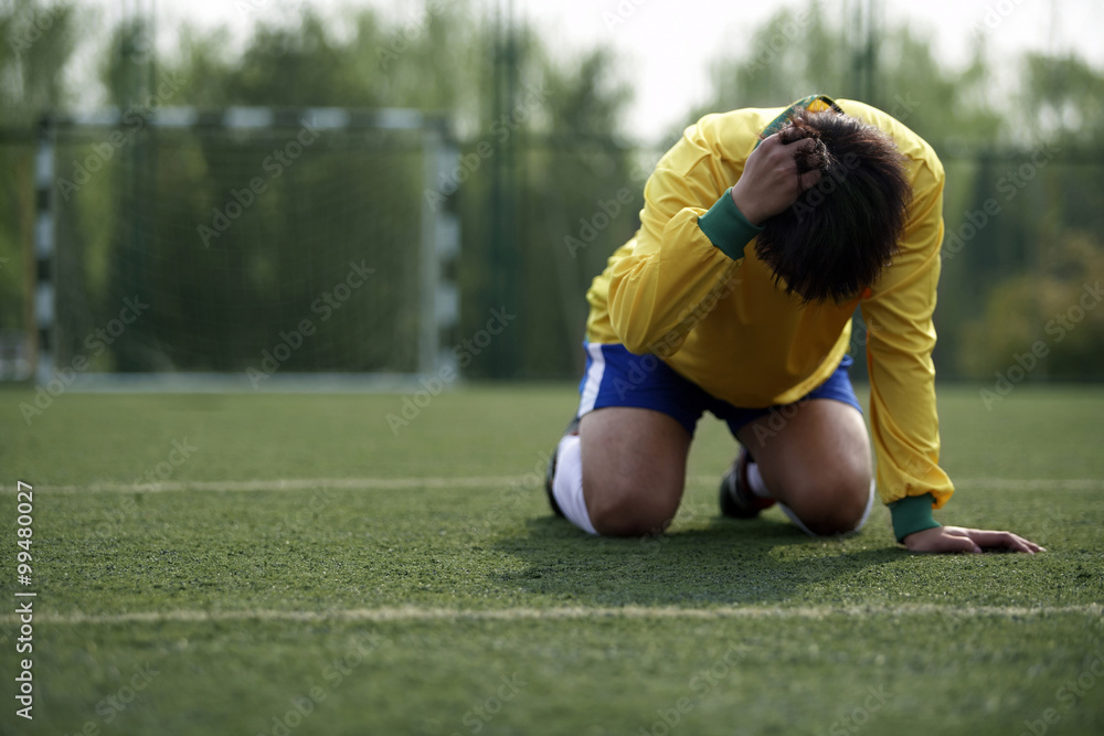 失望的足球运动员跪在地上