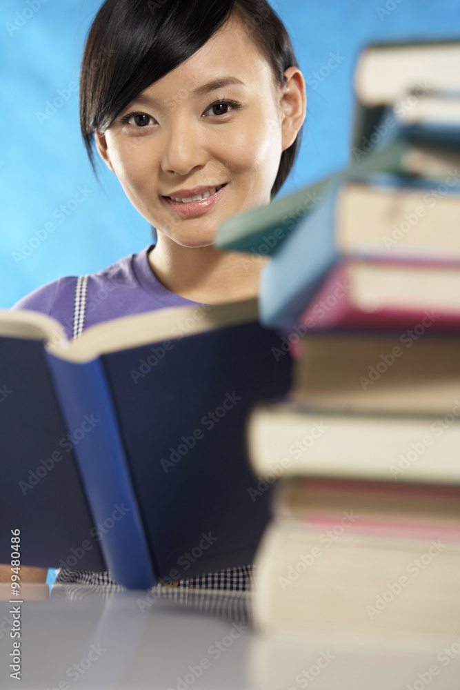 年轻女人在一摞书后面看书
