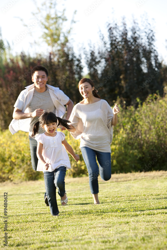 年轻的中国家庭在田野里奔跑