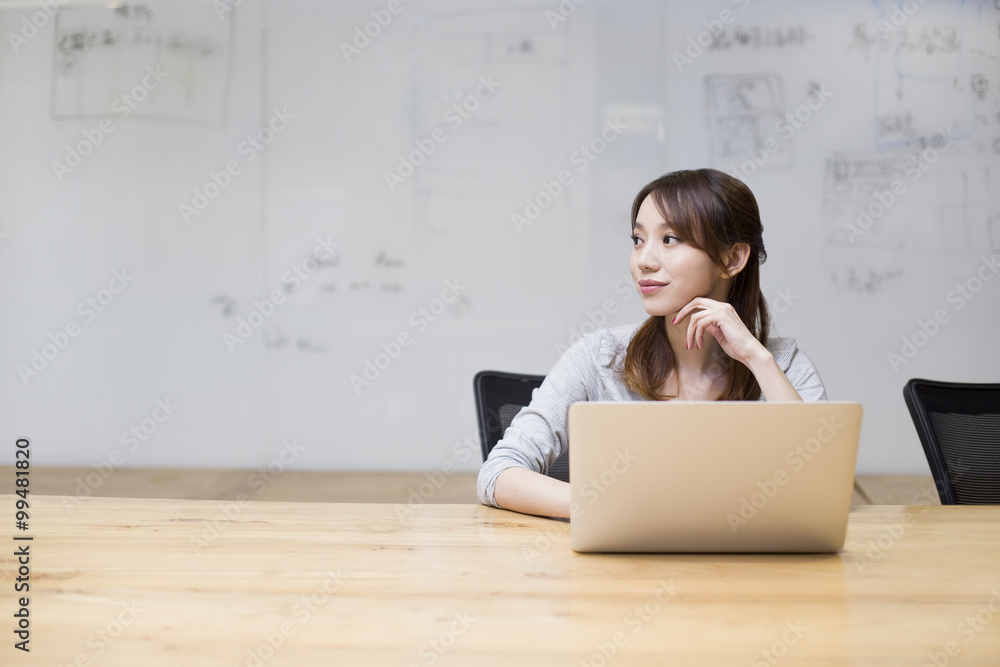 Young woman using laptop in board room