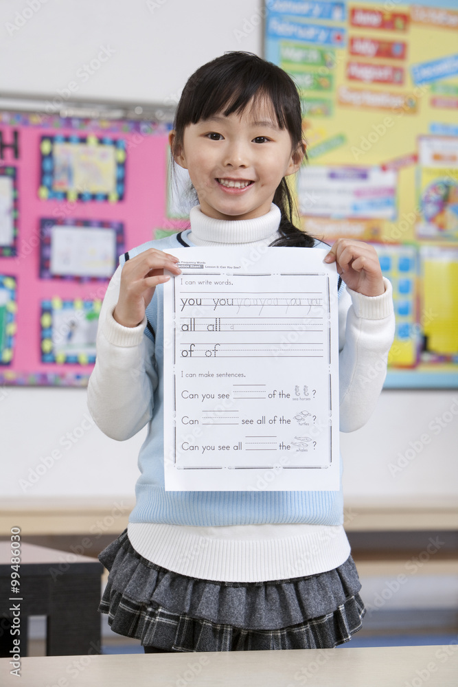 Young student holding homework in classroom