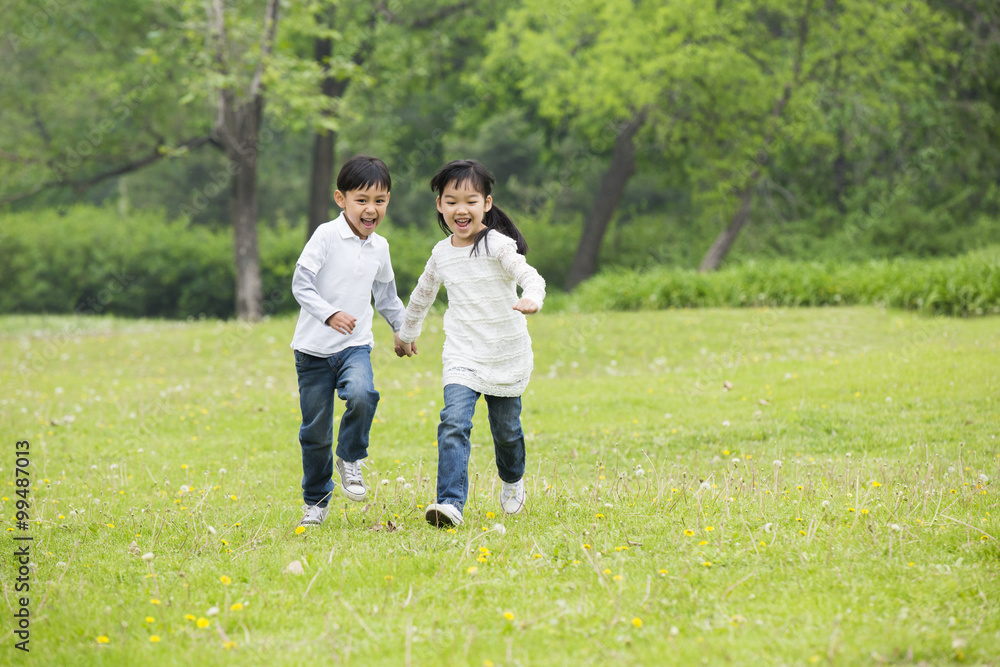 Happy children holding hands running on the grass