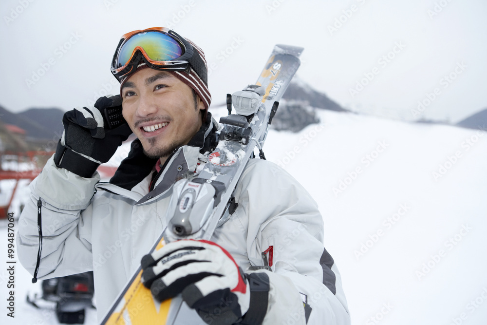 男子站在滑雪场上，用手机交谈