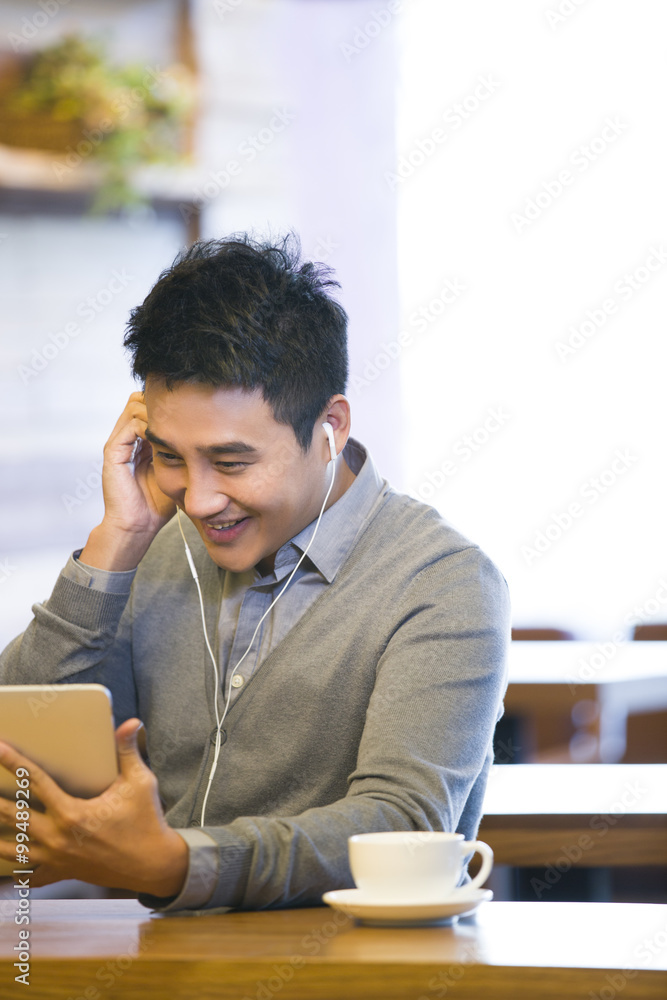 年轻人在咖啡馆用数字平板电脑欣赏视频