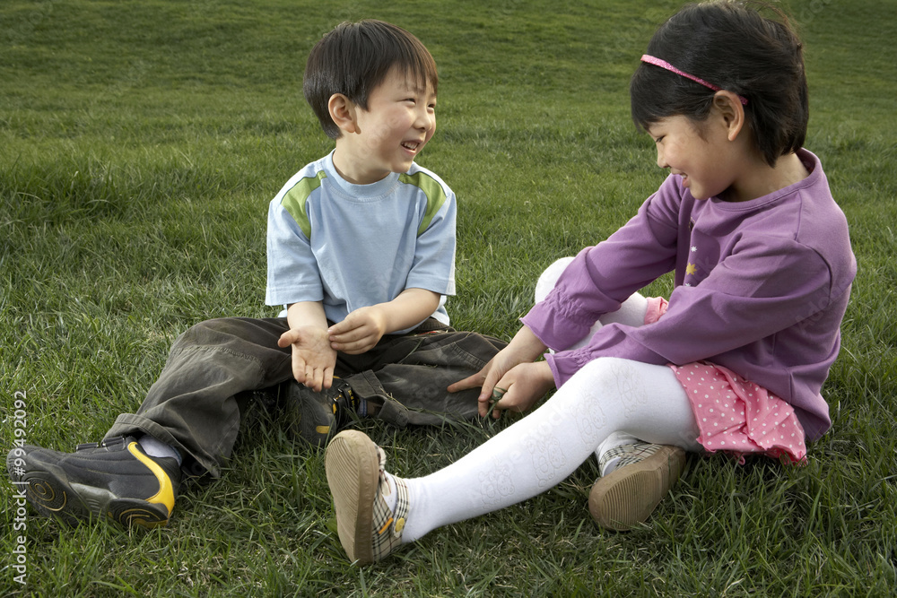 Young Boy And Young Girl Sitting In The Park Talking