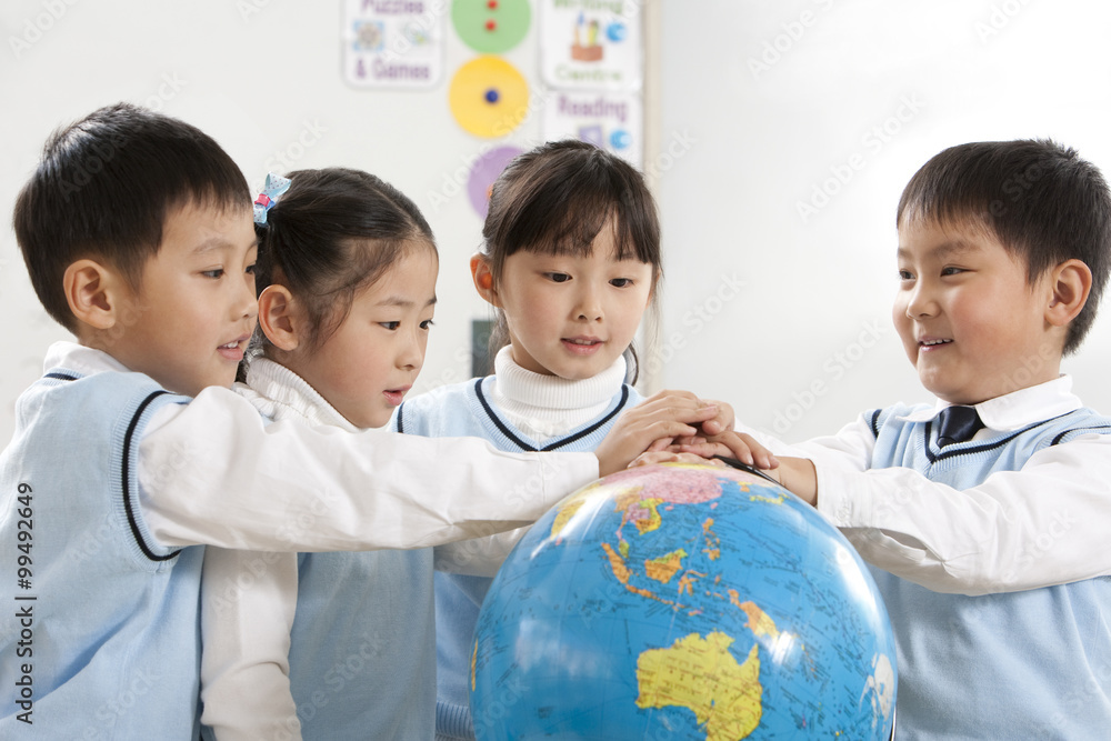 Four curious young students gathered around a globe