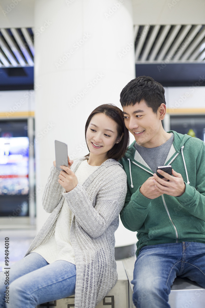 年轻夫妇在地铁站使用智能手机