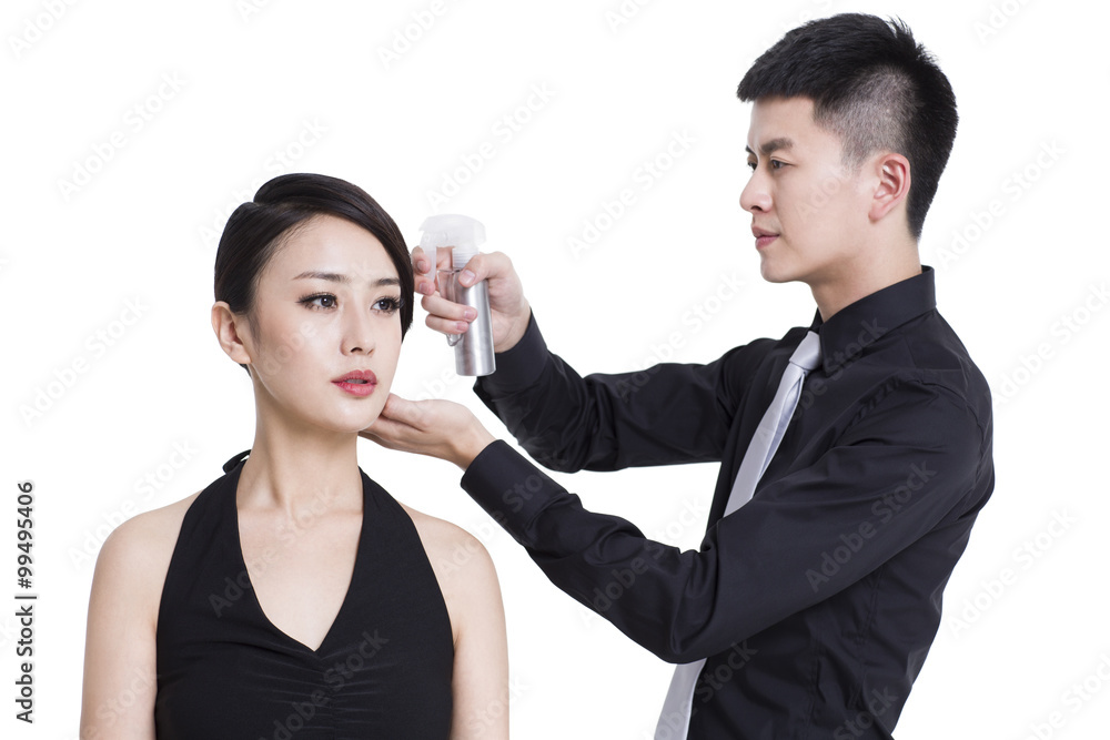 Young woman getting her hair done by makeup artist