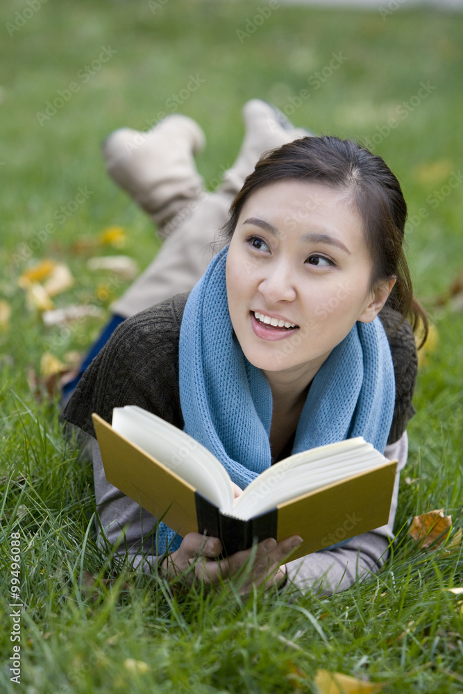 一个年轻女人躺在草地上看书
