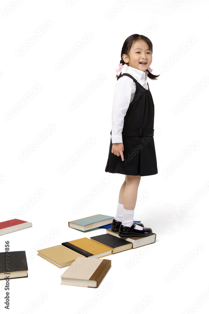 小女孩站在一些书上