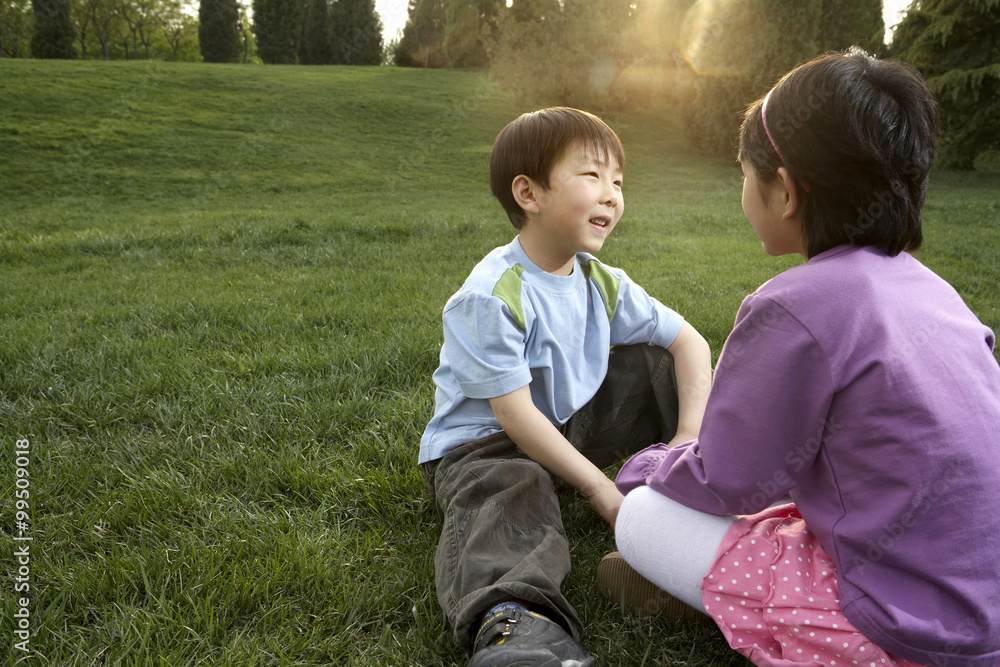 坐在公园里聊天的年轻男孩和年轻女孩