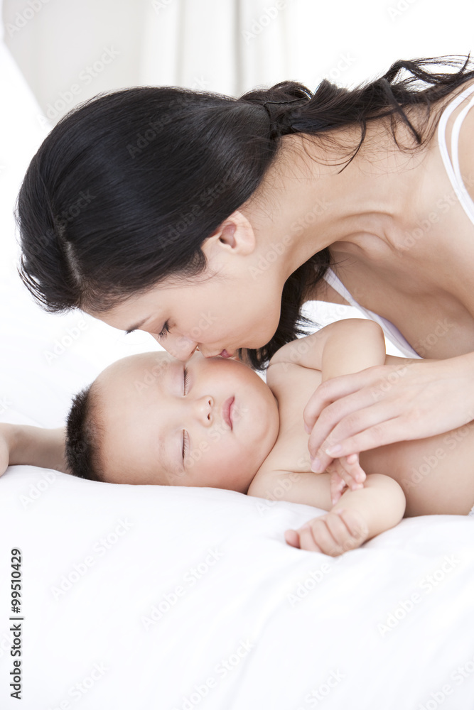 Mother kissing sleeping baby tenderly
